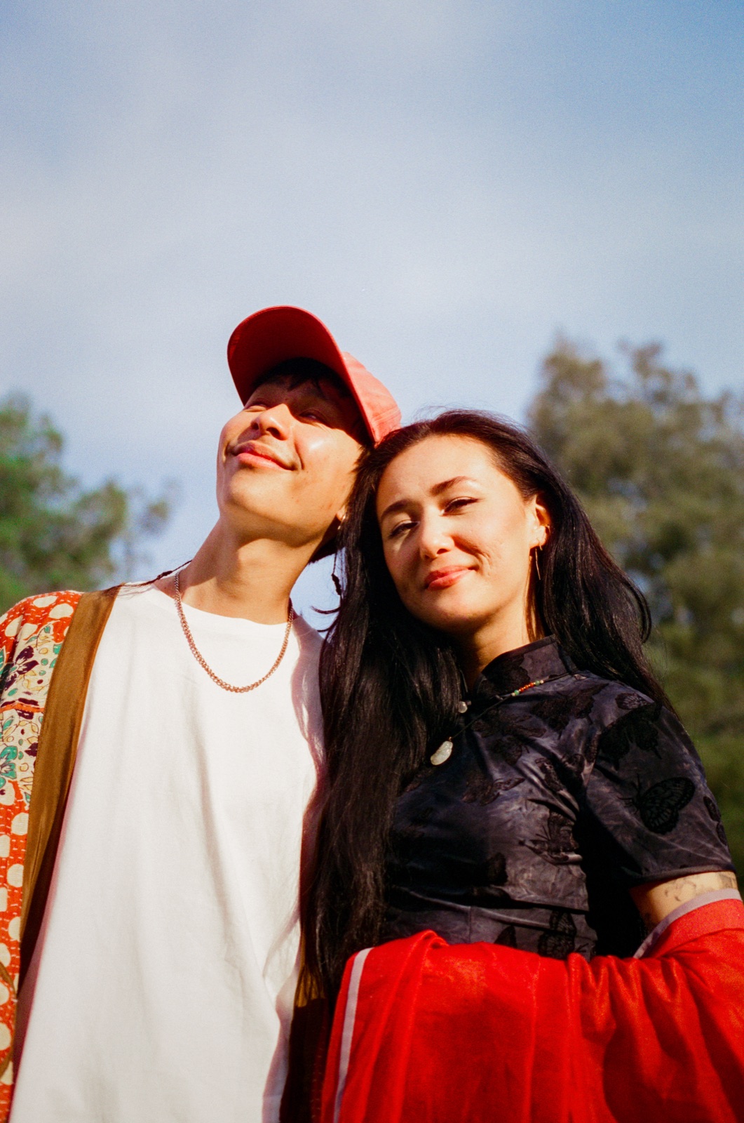 dān dān and Jefferson Chen lean their heads together under a pale blue sky