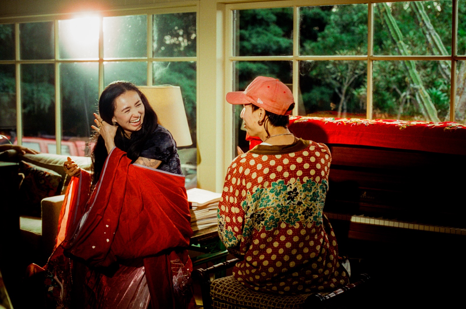 dān dān laughs beside a piano draped in red embroidered fabric